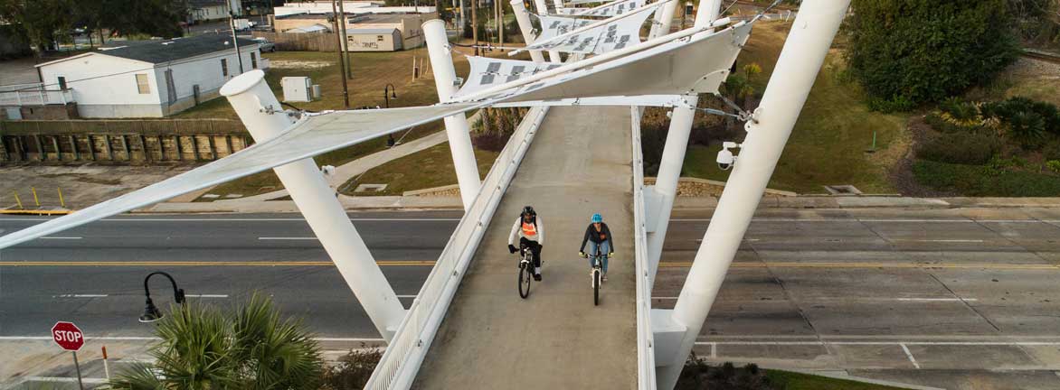 Two bikers trafeling aross the padestrian bridge
